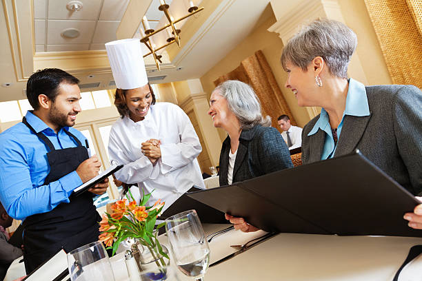 Restaurant chef and waiter helping diners with menu food questions
